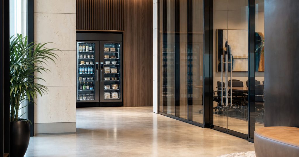 Revvolto smart vending cooler in an Austin business event lounge with stocked clear glass shelves