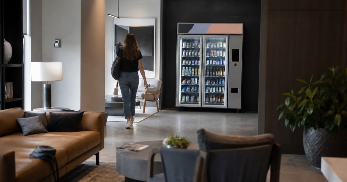Conceptual Revvolto smart vending machine in an apartment amenity lounge with stocked glass doors